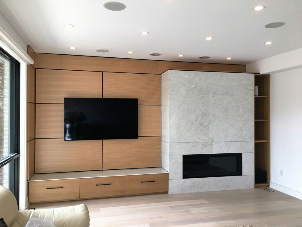 Rift white oak media wall with shadow-line reveals, floating bench and a stone-clad linear gas fireplace
